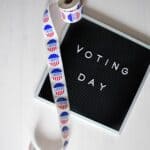 DeSoto County Absentee Voting Now Open in Hernando Voting Day sign beside a roll of I Voted stickers, illustrating DeSoto County absentee voting