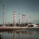 xAI Offers to Buy Southaven Homes Near Noisy Power Plant Natural gas power plant with chimneys reflected in a reservoir, illustrating the xAI Southaven power plant story