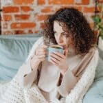The 5 Best Electric Heated Throws for DeSoto County Cozy Fall Nights Woman wrapped in a cozy throw blanket with a warm drink on a fall evening