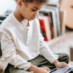 The 5 Best Kids' Tablets for School and Travel for DeSoto County Families A young child sitting on a rug at home, focused on a tablet held in both hands