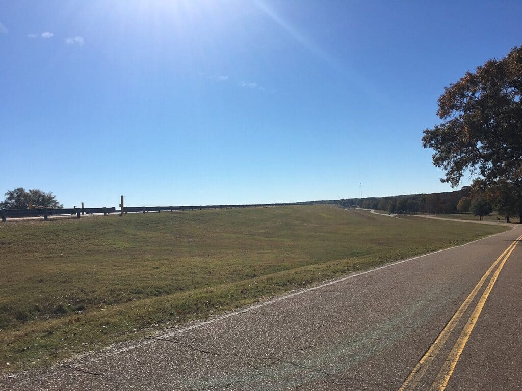 Grass-covered embankment of Arkabutla Dam beside the dam road in DeSoto County, site of ongoing Arkabutla Dam repairs