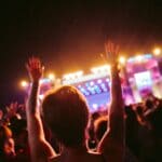 Free Rodney Atkins Concert in Southaven Set for Oct. 15 Fan with arms raised in front of a lit outdoor concert stage, illustrating the free Rodney Atkins Southaven concert