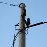 Hernando Phone Outage After Roundabout Crew Hits C Spire Line Telephone pole with phone cables against a blue sky, illustrating the Hernando phone outage
