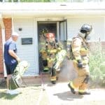 Olive Branch House Fire: 2 People, 5 Dogs Rescued Firefighters in turnout gear exit a smoke-filled house during a training exercise, illustrating the Olive Branch house fire rescue