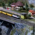 Olive Branch Model Train Show Draws Rail Fans of All Ages Miniature model railway with a yellow train crossing a bridge, like layouts at the Olive Branch model train show